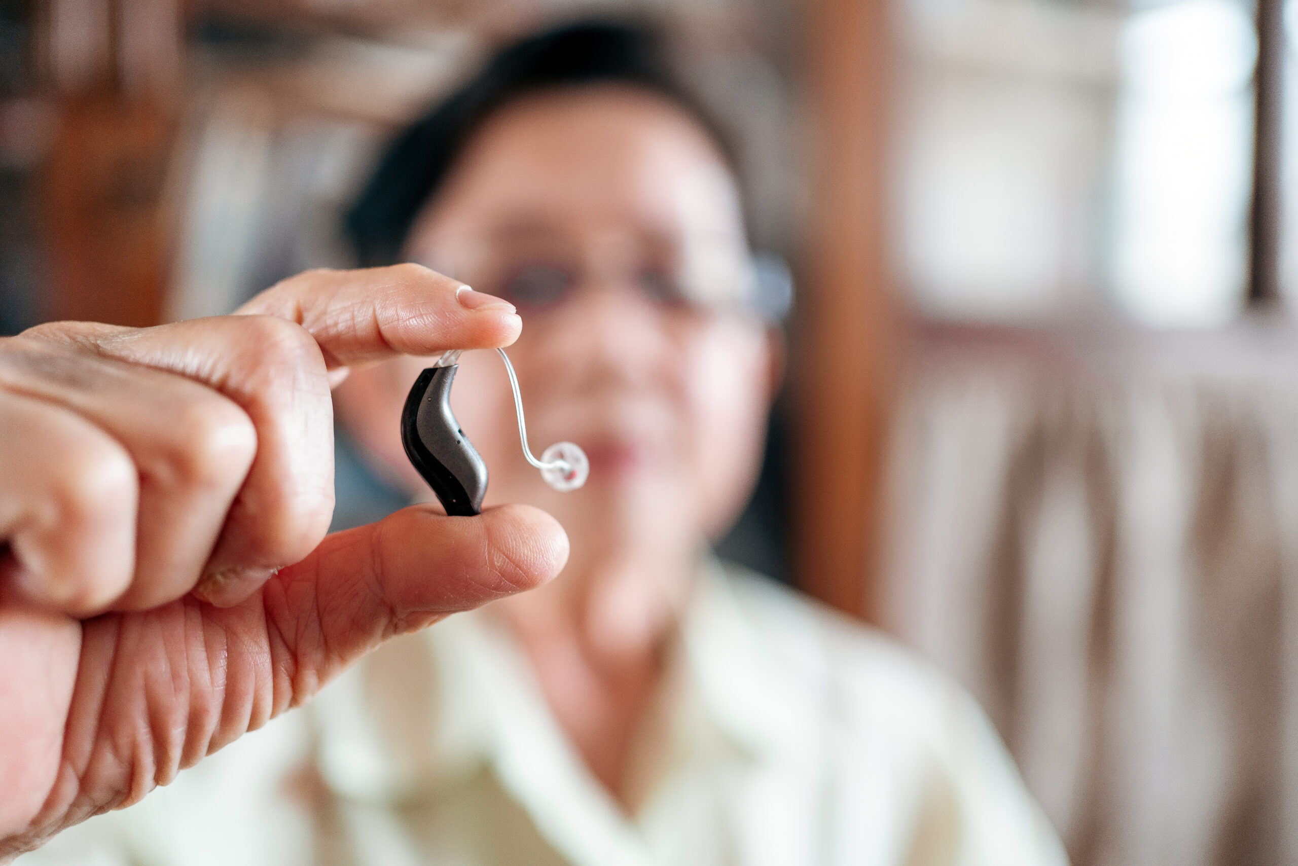 Senior Woman Holding A Modern Hearing Aid Device, Symbolizing Ad